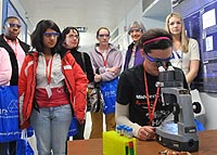 Dana Bielinski peers into a microscope while other students and teachers look on at Science Careers in Search of Women.