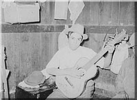 Mexican boy playing guitar in room of corral. Robstown, Texas