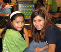 Photo of a student demonstrating a computer game she developed to another student.