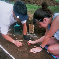 Teachers excavate pottery from an archeological feature.