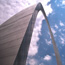 Looking up at the Gateway Arch with clouds in the sky.