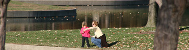 Woman pointing out something on the Gateway Arch grounds to a child.