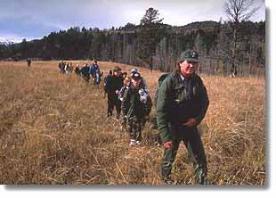 A park ranger leads a group of children on a hike.