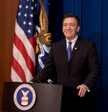 image of former assistant secretary Neil Romano standing behind a podium