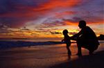 A father plays with his son during sunrise at Kailua Beach in Hawaii, October 19, 2003. REUTERS/Lucy Pemoni