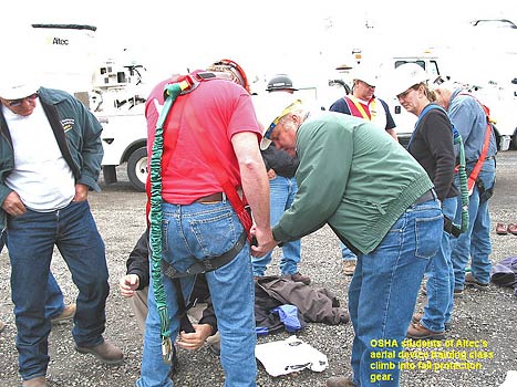 OSHA students of Altec's aerial device training class climb into fall protection gear