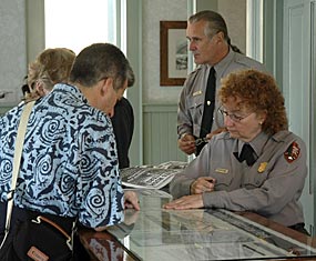 a male and a female ranger provide information to two visitors at an information desk