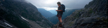 Hiker on rocky summit with clouds and mountains in background Photo credit: J Eve Griffin