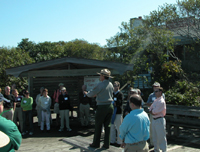 Park ranger talks to group of adults on platform in front of visitor center.