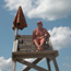 Lifeguard sits on stand, watching over beach.