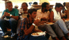 Several Cuban migrants under a tent during meal time (on a Coast Guard cutter).