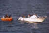 A picture of a white pleasure craft with a Coast Guard small boat alongside.