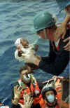Another picture of a baby being lifted aboard a Coast Guard Cutter.
