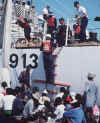 A picture of several Haitian migrants climbing up a rope ladder to a Coast Guard cutter.