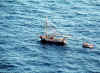 A picture taken from an aircraft of a Coast Guard small boat approaching a sailboat with Haitian migrants onboard.