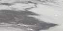 Close view of sand showing bands of colors: white, dark grey, and reddish purple.