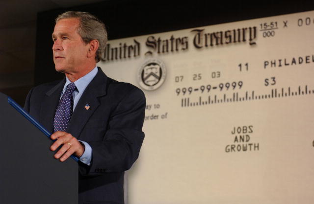 A picture of President George W, Bush standing behind a podium with an enlarged tax relief check in the background.