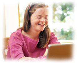 Photograph of a girl with Down's Syndrome using a laptop.