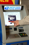 Image 7: Close-up of a hand using an Automated Postal Center (APC) screen.