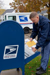 Image 2: A letter carrier empties a collection box.