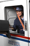 Image 10: A smiling letter carrier in her LLV making a mailbox delivery.