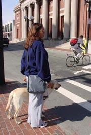 A woman waits to cross a downtown street.
