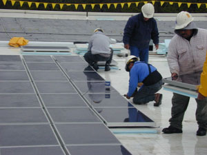 Workers installing solar panels on rooftop of RTP's NCC building.