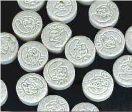 Photograph of several round, white pills with a stamped image of a Smurf.