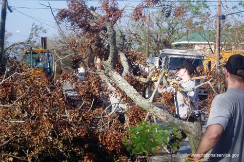 AmeriCorps members remove downed trees and other burnable debris from the roadside in Pass Christian, Miss.