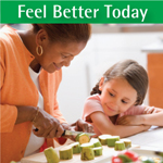 Child watching adult woman prepare food by chopping vegetables