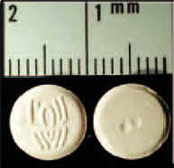 Photograph showing two white tablets beneath a ruler. Each tablet is 1 centimeter wide, one has a spider logo.