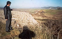 Mr. Hysin Shamata points out a garbage mound that will soon be covered in grass.