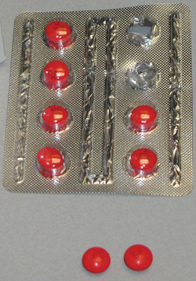 Photo showing an 8-pack of Coricidin® HBP Cough & Cold tablets; two are displayed outside of the foil package.