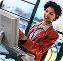 A woman, smiling,  looking at a computer.