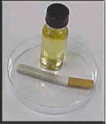 Image of a cigarette lying below a small vial of liquid.