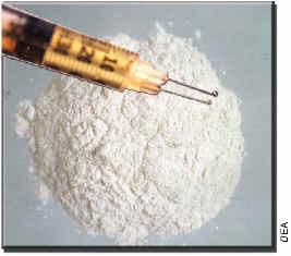 Photograph of hypodermic needle over a white powder substance.