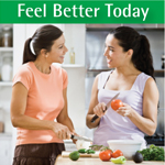 Two young women preparing a meal by chopping vegetables, talking and smiling