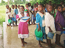 Photo of a school feeding program in Malawi, children receive porridge fortified with iron and other micronutrients.