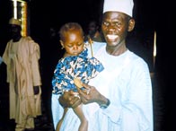 Photo of a Nigerian man holding his daughter and smiling.