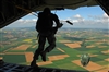 U.S. Air Force and Army paratroopers jump from the tail gate of a C-130J Super Hercules cargo aircraft.