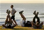 A jogger (2nd L) passes fitness enthusiasts performing stretching exercises after sunrise at Queenscliff Beach in Sydney, September 1, 2008. REUTERS/Will Burgess