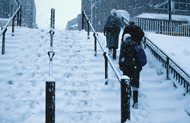 People walking up snowy subway stairs