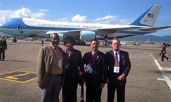 Photo of Ramesh Lutchmedial, Director General of Trinidad and Tobago Civil Aviation Authority; Loretta McNeir, TSA Representative; and Transportation Security Inspectors Kevin Yap-Sam and Thomas Finneman standing near Air Force One.