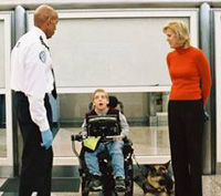 Photo of a TSO standing next to a boy in a wheelchair, wih his mom next to him.