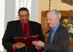 Scott T. Johnson (right), director of field operations, Security Operations, hands former FSD Willie Williams a plaque with a picture of the Pentagon on 9/11.