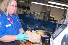 TSO Malinda Pound screens the contents of a checked bag after it alarmed in the new inline baggage screening system at Ontario International Airport. 
