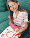 A girl with a broken arm, smiling, drawing on a piece of paper.