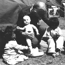 Relief worker caring for three small children left homeless due to an earthquake in Guatemala, 1976.