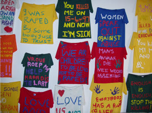 photo of 15 hand made t-shirts reading different statements such as I was raped by somebody I used to trust, you killed me on 15-4-97 and now I'm sick, women speak out against abuse, we are children to be loved not to be raped, vroue roep na help maar dis te taat.