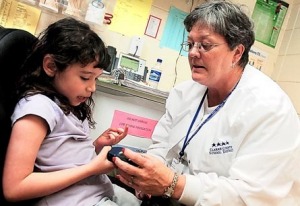 Jade Poindexter, a kindergartner at Timothy Road Elementary School, checks her blood in the clinic recently with nurse Julie Westphal.